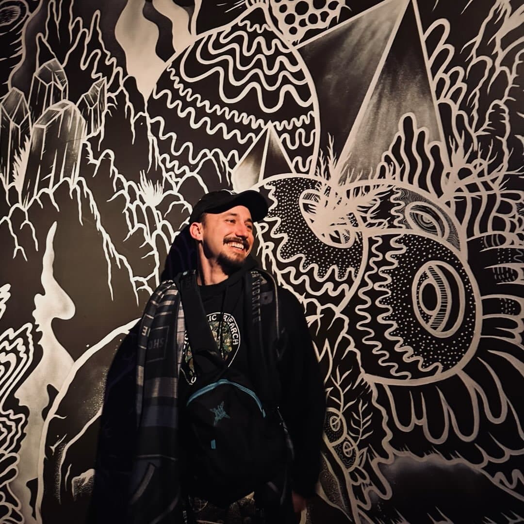 Jeramiah Coffey in front of a black-and-white psychedelic mural